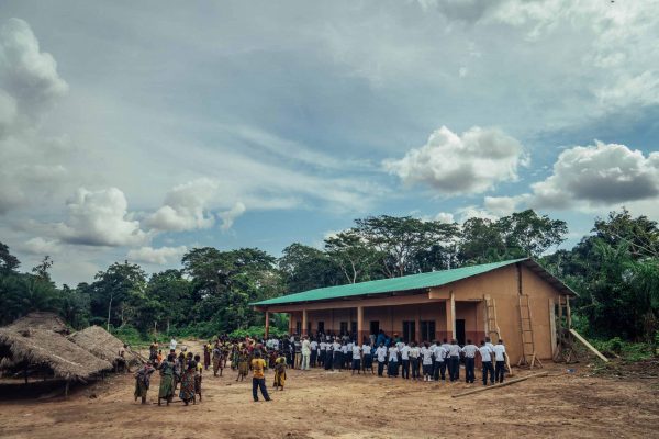 Enfants et visiteurs rassemblés devant une école dans le projet Mai Ndombe, RDC. Crédit photo : Filip C. Agoo pour Wildlife Works Carbon.