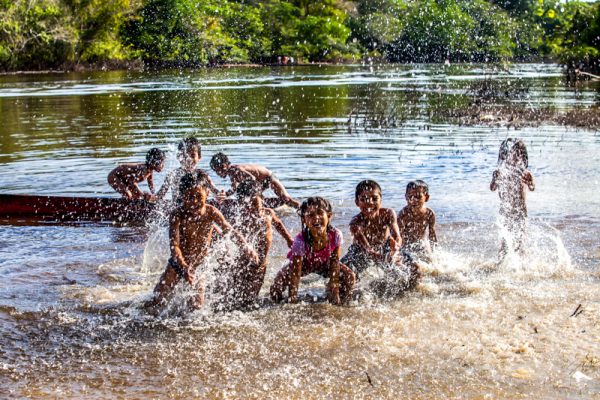 Kinderen spetteren in het water in het Nii Kaniti project, Peru.